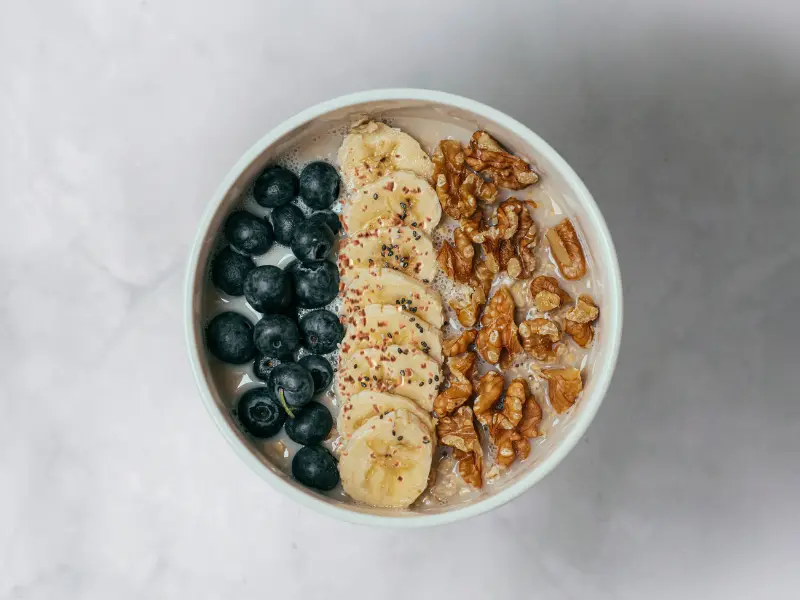 Bowl of oatmeal with blueberries, bananas and walnuts on the top. 