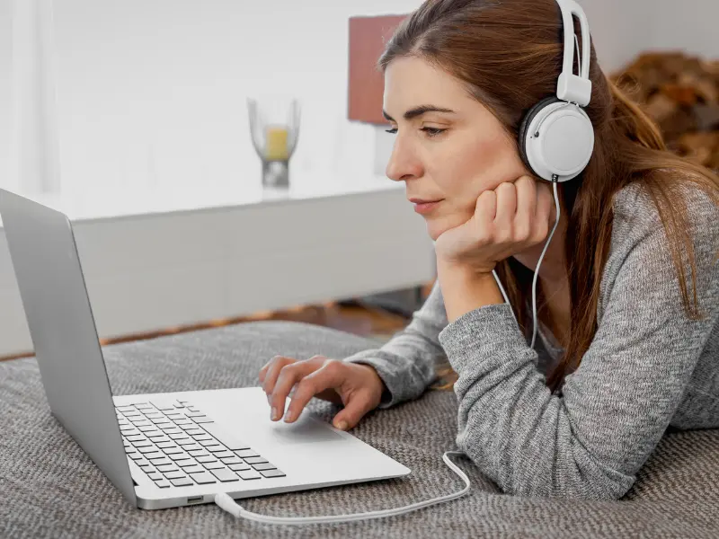 A woman wearing headphones looking with focus at his computer. 