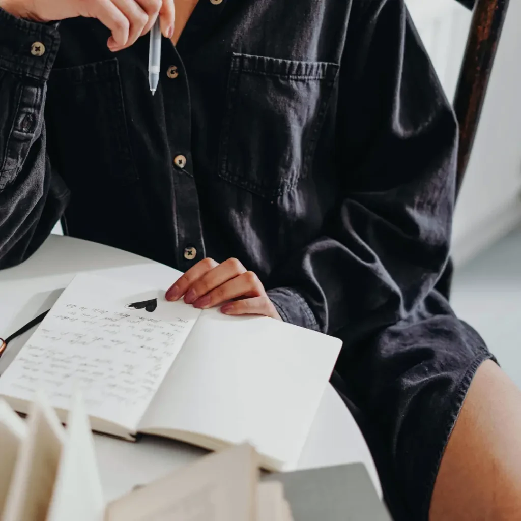 woman sitting at the table with her journal opened and pen in her hand.