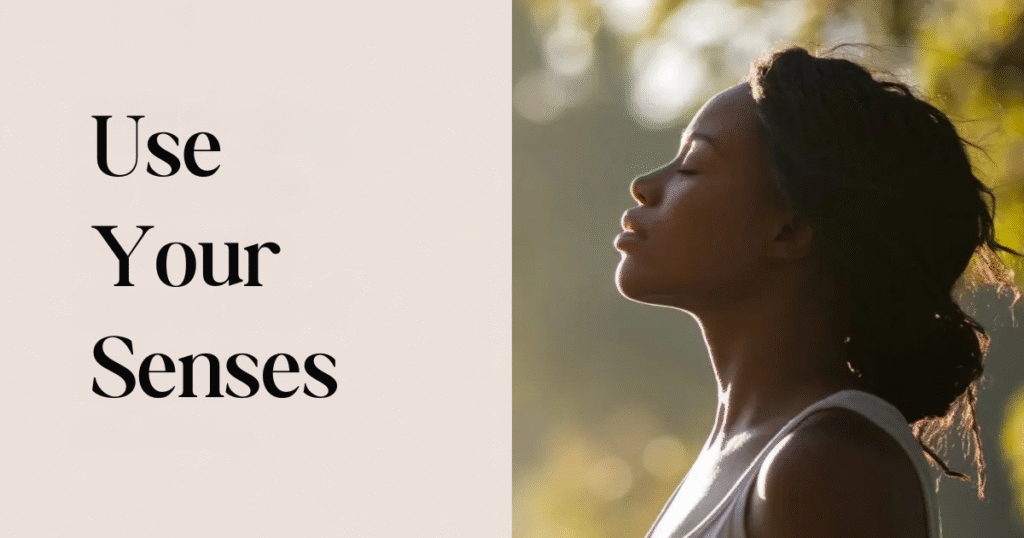 Woman standing outdoors with eyes closed in peaceful sunlight beside the words “Use Your Senses,” symbolizing living with mindfulness, using your senses, and finding calm.