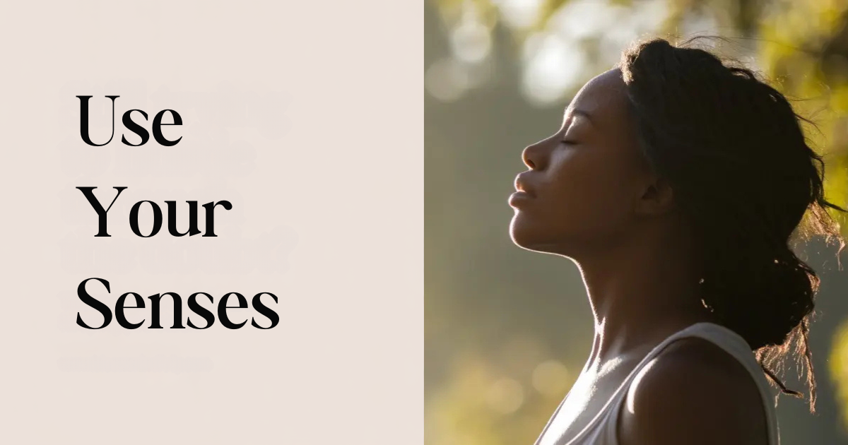 Woman standing outdoors with eyes closed in peaceful sunlight beside the words “Use Your Senses,” symbolizing living with mindfulness, using your senses, and finding calm.