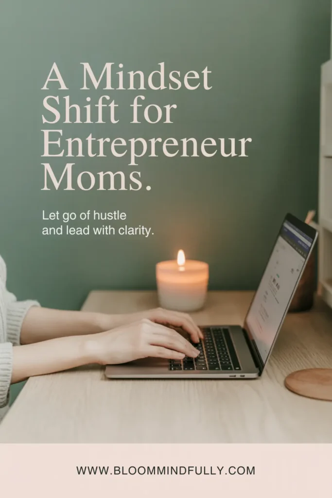 A woman types on a laptop with a lit candle nearby, overlaid with text that says “A Mindset Shift for Entrepreneur Moms. Let go of hustle and lead with clarity.” Promotes a mindset shift for entrepreneur moms.